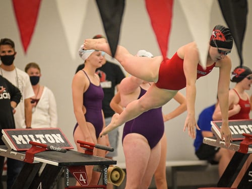 girls swim student diving into water