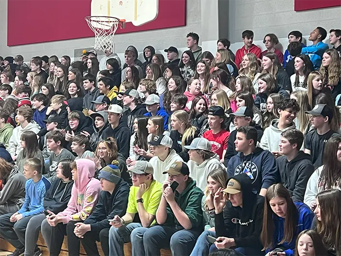 students crowd in gym seats